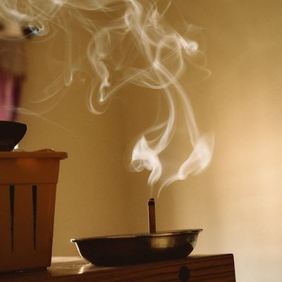 A single incense stick burning in a minimalist room